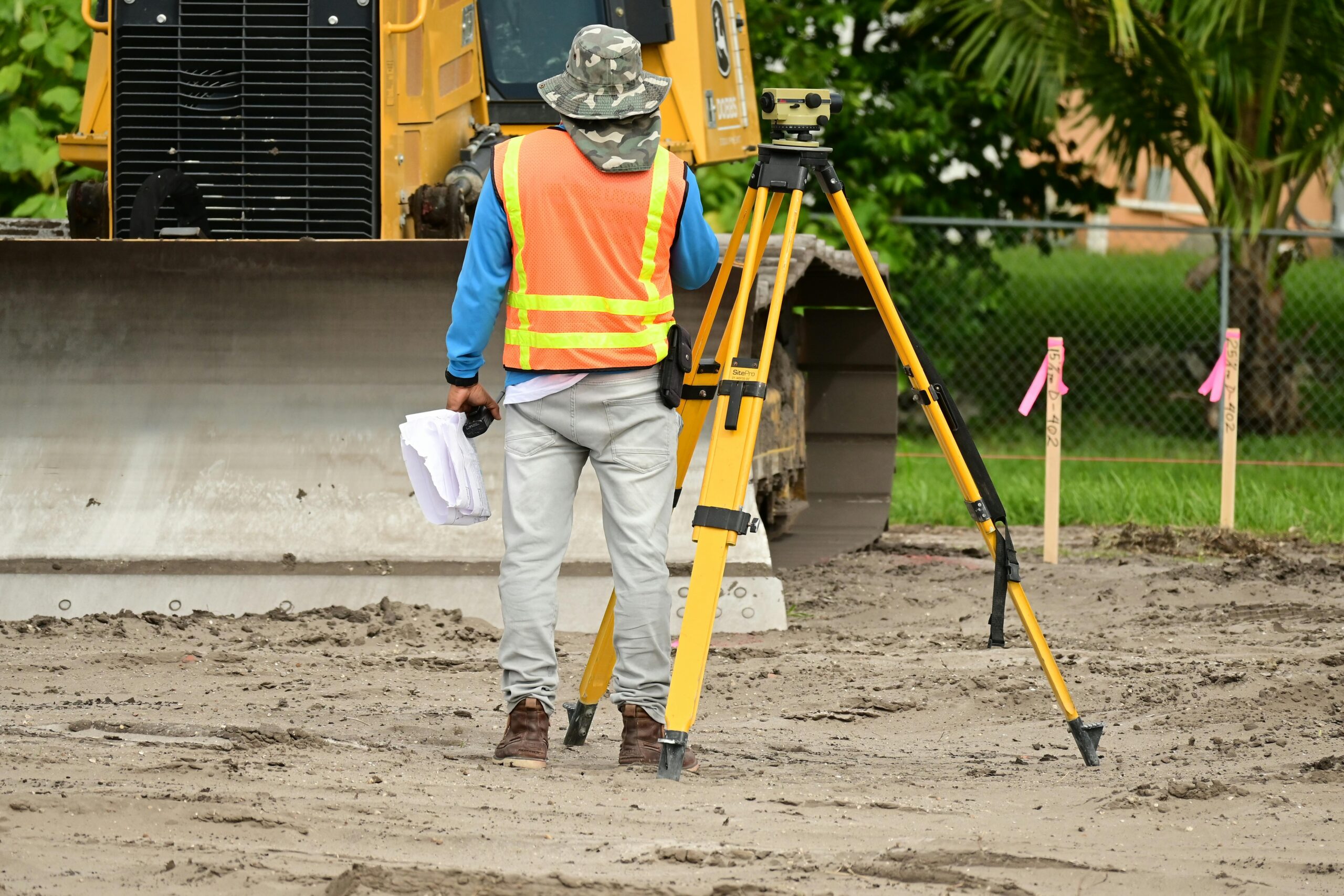 photo-hero-15 A surveyor with equipment conducts measurements on a construction site.